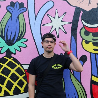 Aaron seated in front of a brightly painted mural