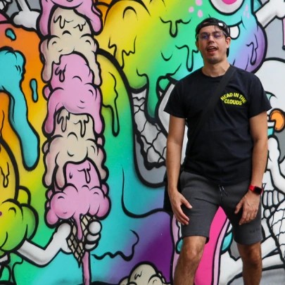 Aaron standing in front of a brightly painted mural