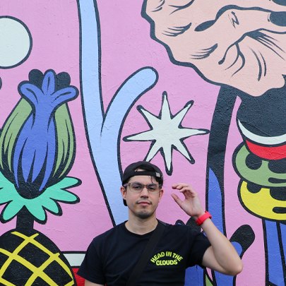 Aaron seated in front of a brightly painted mural